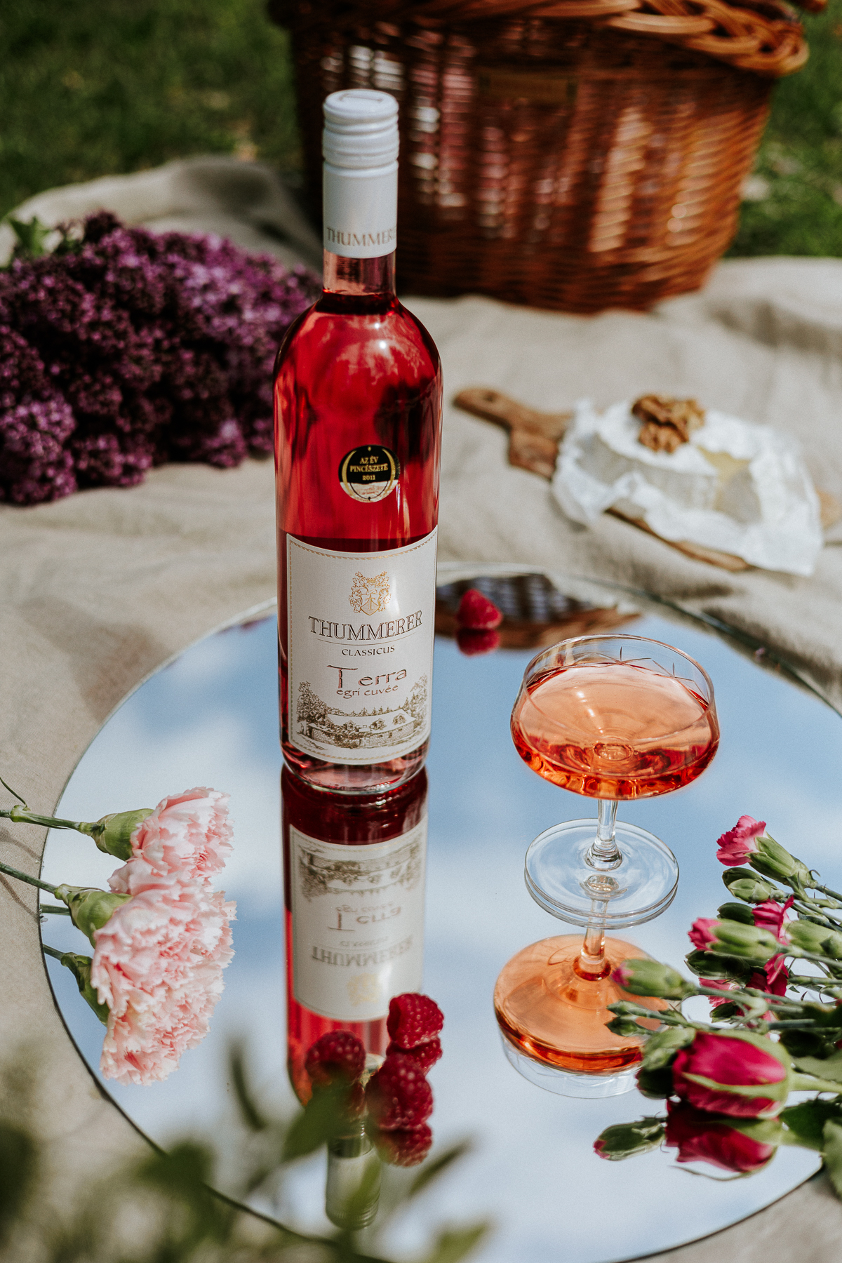Egy palack Terra Egri Rosé Cuvée 2024 állítva egy tükröződő asztalon, hangulatos díszletben.