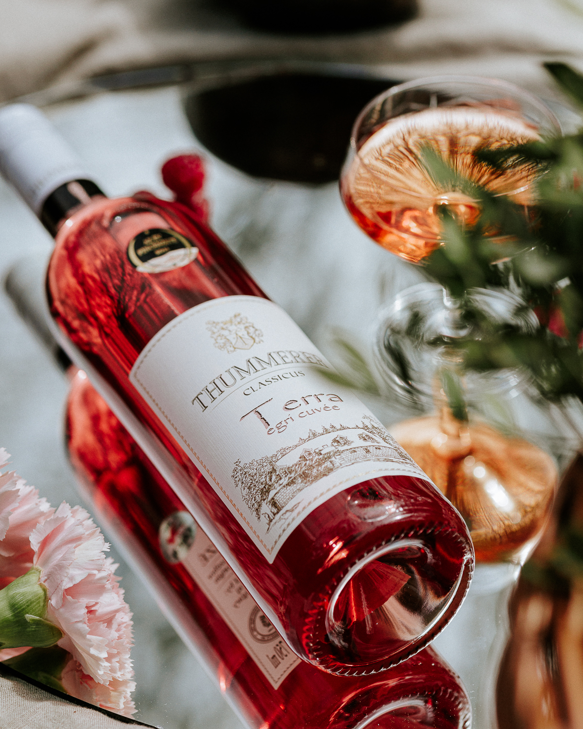 Egy palack Terra Egri Rosé Cuvée 2024 fektetve egy asztalra, mellette pohárban kitöltve a rosé bor.